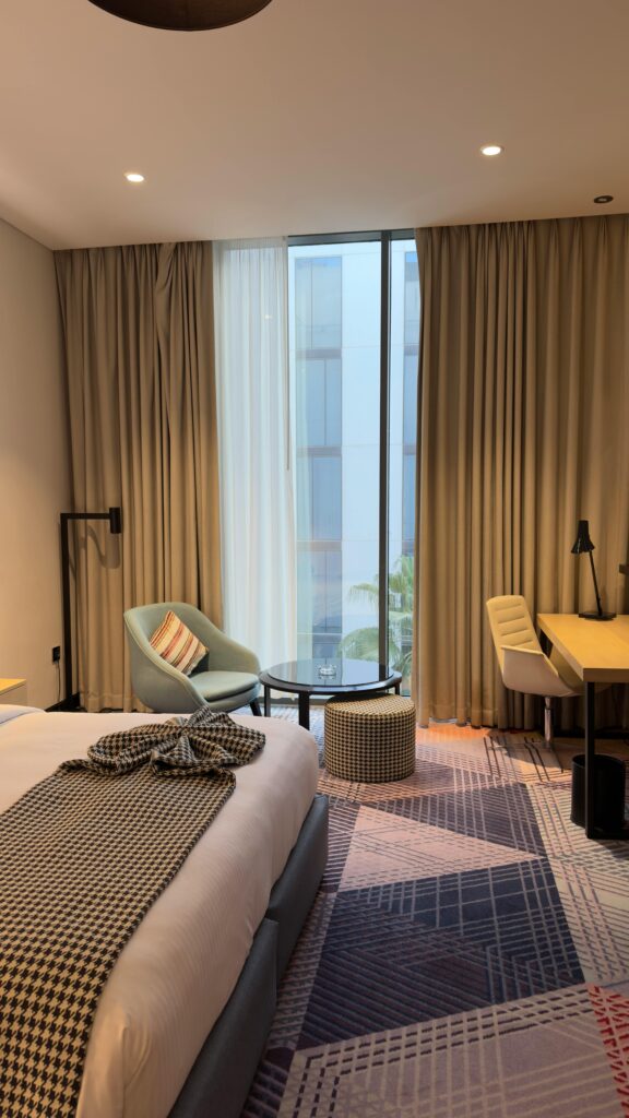 Bright and stylish hotel room in Dubai featuring modern decor and a city view through large windows.