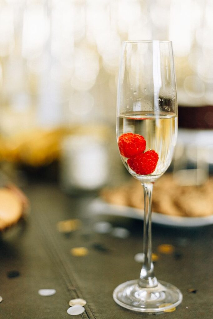 Close-up of a champagne glass with raspberries, perfect for celebrations.