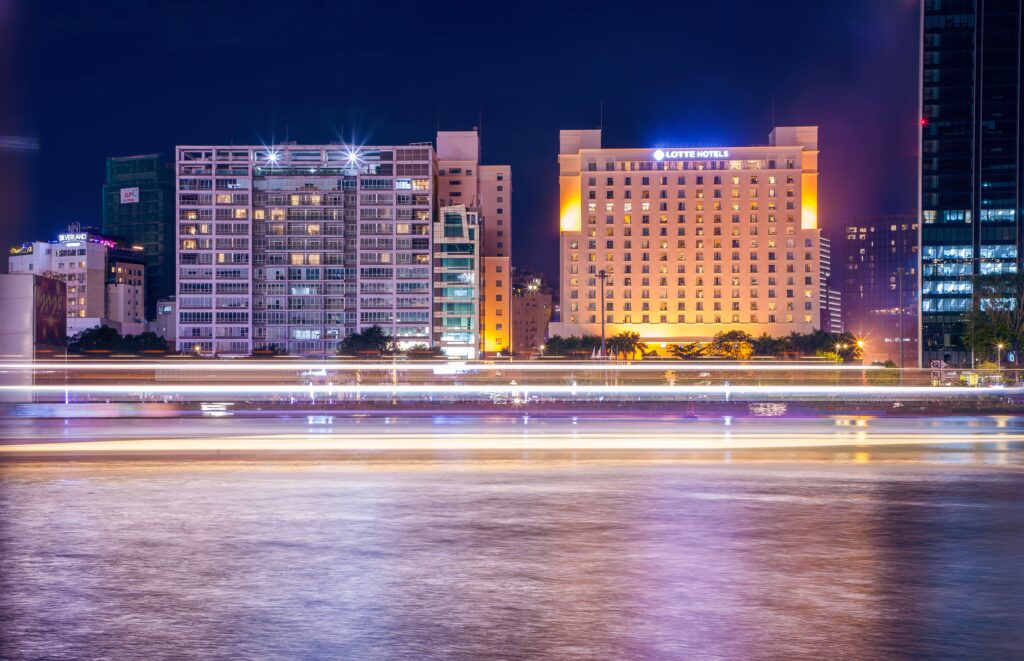 Lotte Hotels illuminated at night with motion lights on a calm riverfront.